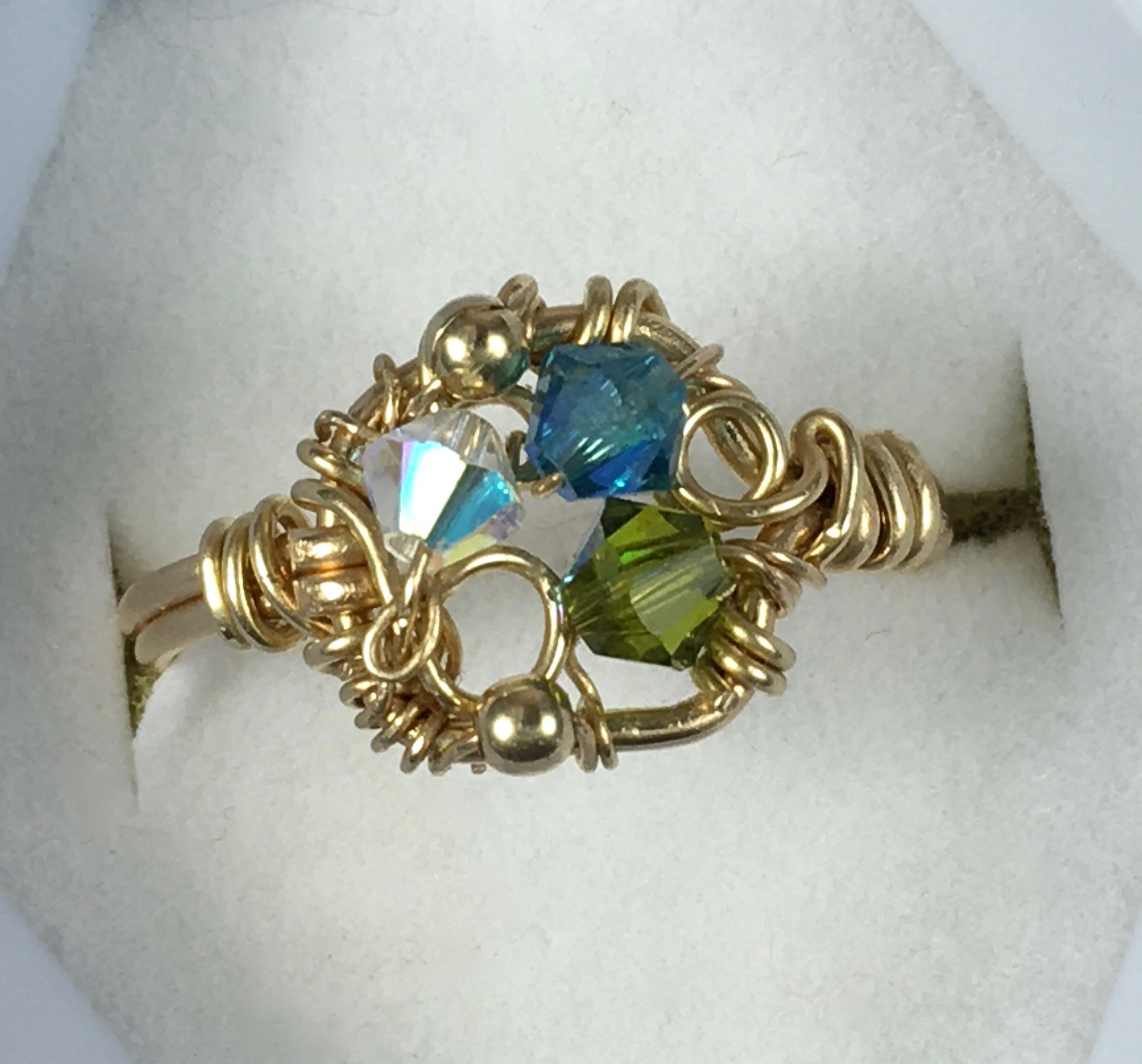 A gold ring with a white, blue and green jewel woven in